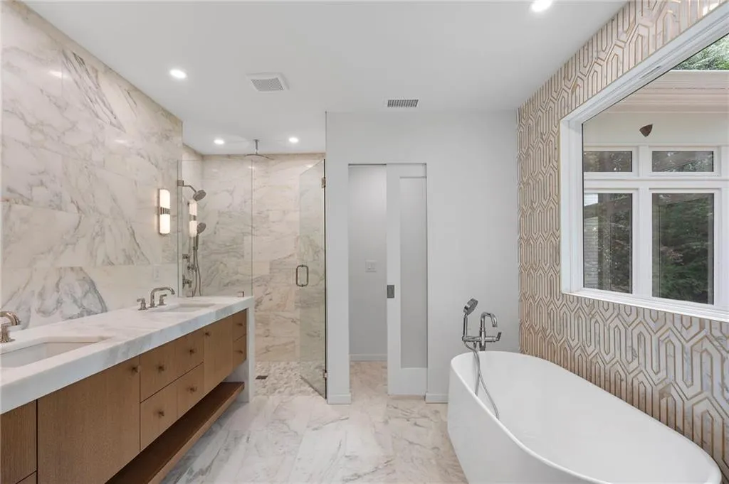Contemporary bathroom featuring a freestanding tub, a geometric patterned accent wall, and a large window