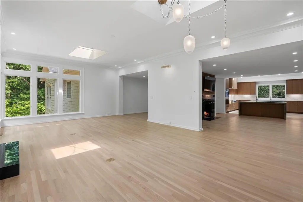 Expansive living area featuring light wood-finish flooring, a large multi-pane window, and a skylight