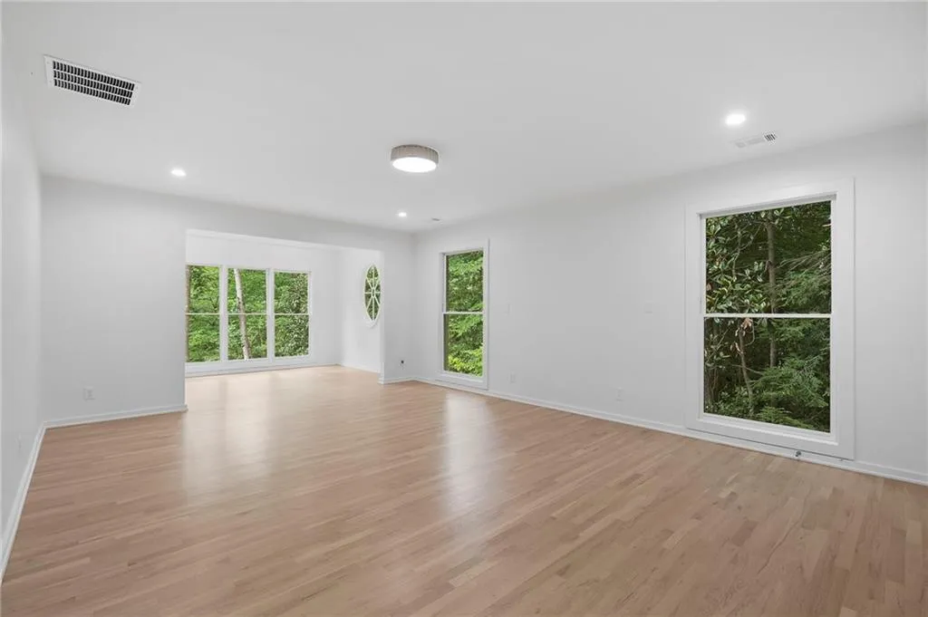 Expansive living area featuring light wood-finish flooring, recessed lighting, and multiple large windows