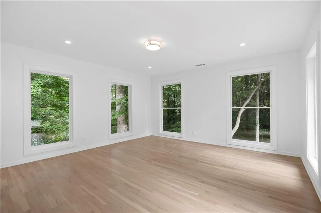 Bright room featuring light wood-finish flooring, white walls, and multiple windows with white trim