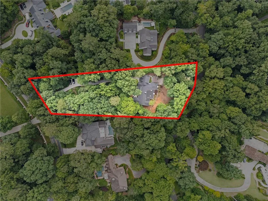 Expansive wooded parcel featuring a private drive, mature tree canopy, and a substantial residence with a dark-toned roof