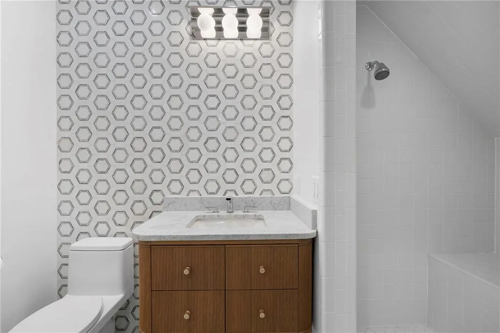 Bathroom featuring a wood-finish vanity with a marble countertop, undermount sink, and polished chrome faucet