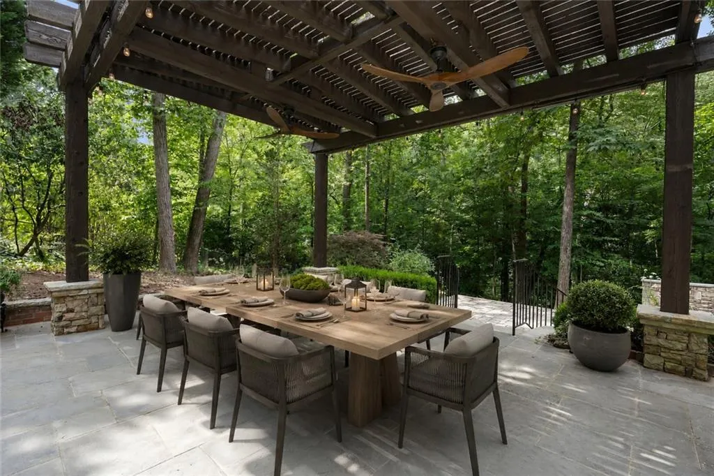 Expansive outdoor living area featuring a wood pergola, integrated ceiling fans, recessed lighting, and stone columns