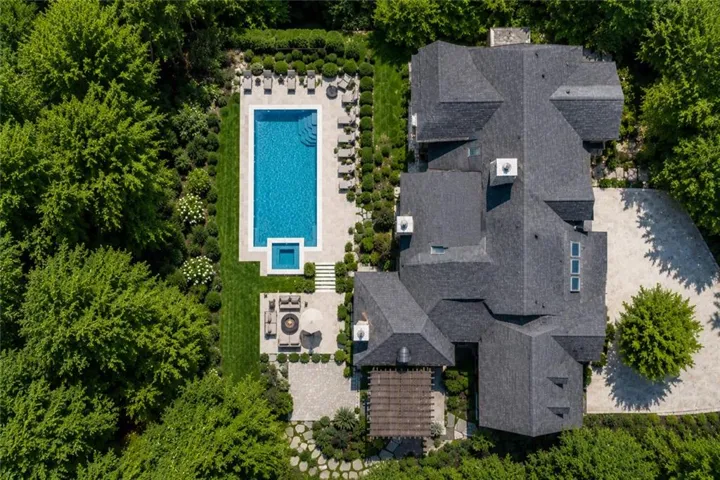 Expansive outdoor oasis featuring a rectangular swimming pool with integrated spa, surrounded by stone paving and manicured landscaping