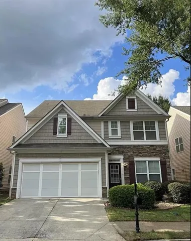 Two-story residence featuring a combination of siding and stone veneer, an attached two-car garage, and a covered entry