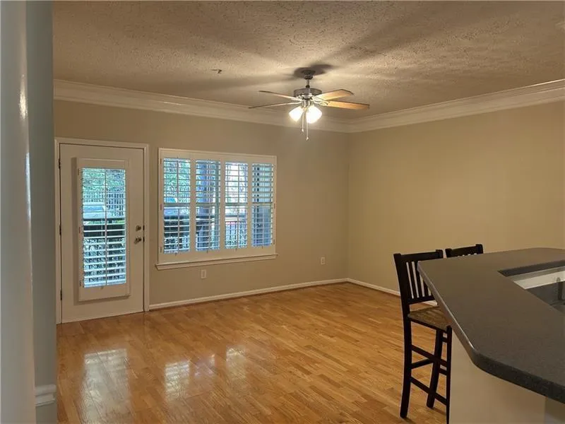 Unfurnished dining area featuring crown molding, light hardwood / wood-style floors, a textured ceiling, and ceiling fan