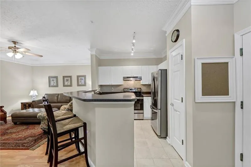 Kitchen with crown molding, stainless steel appliances, a kitchen bar, decorative backsplash, and white cabinets