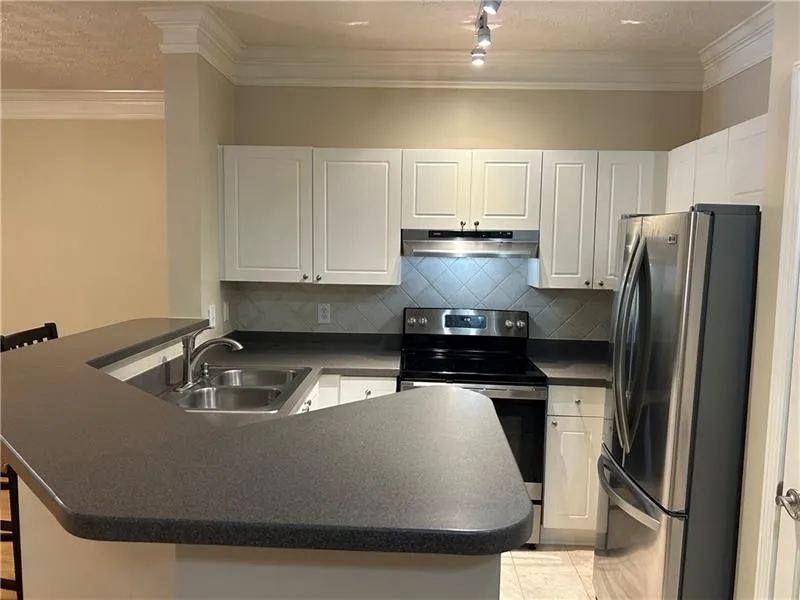Kitchen with light tile patterned flooring, white cabinetry, sink, appliances with stainless steel finishes, and a kitchen breakfast bar