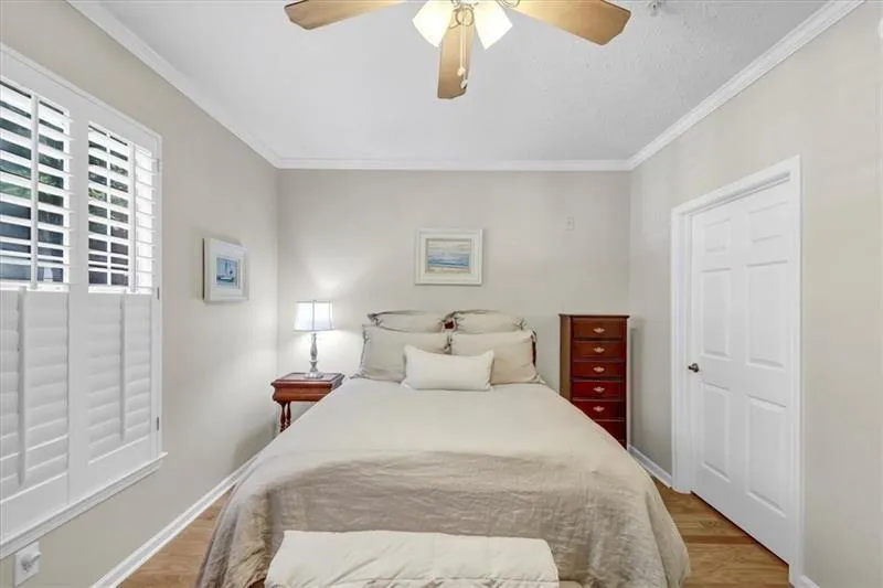 Bedroom with light hardwood / wood-style floors, ceiling fan, and crown molding