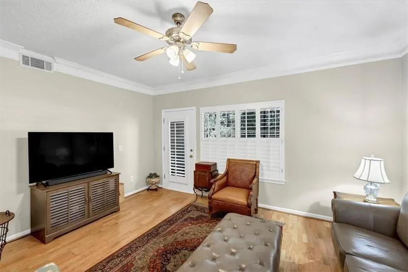 Living room with hardwood / wood-style floors, ceiling fan, and crown molding