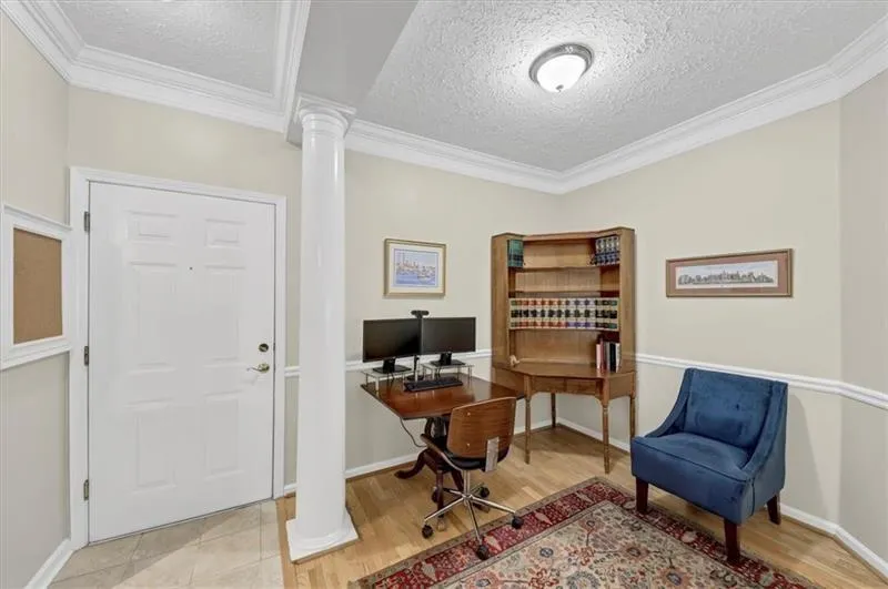 Office featuring a textured ceiling, ornate columns, and light hardwood / wood-style flooring