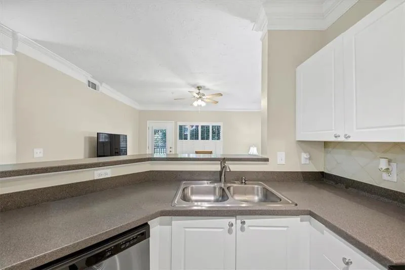 Kitchen featuring white cabinets, sink, tasteful backsplash, ornamental molding, and stainless steel dishwasher