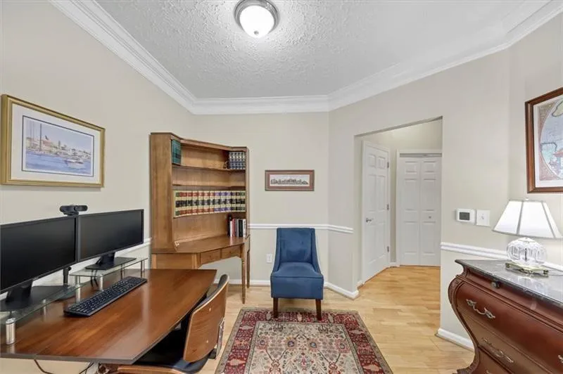 Home office with light wood-type flooring, a textured ceiling, and crown molding