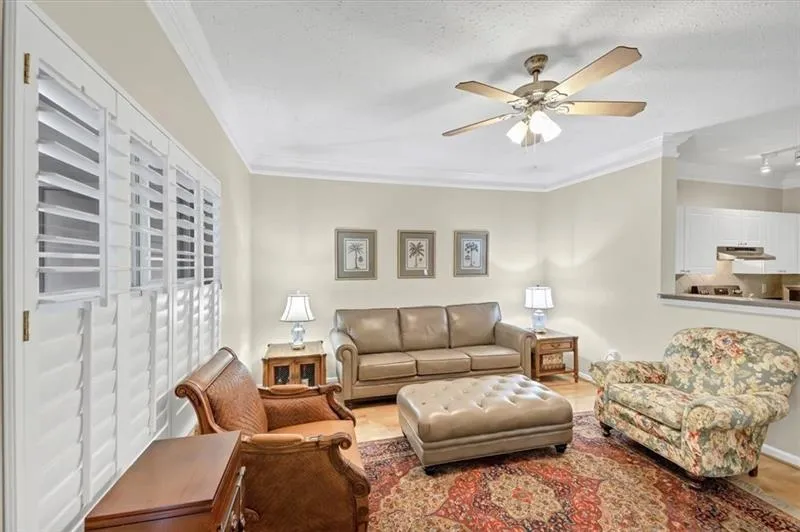 Living room with hardwood / wood-style flooring, ceiling fan, and crown molding
