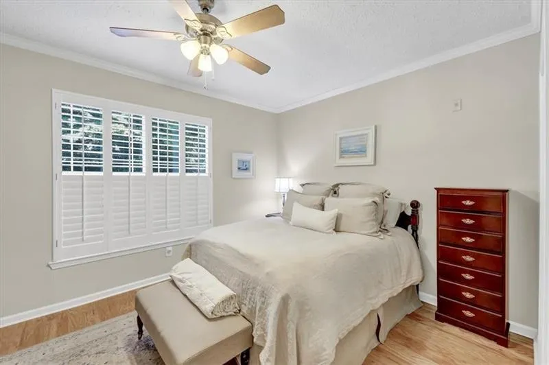 Bedroom with ornamental molding, light hardwood / wood-style floors, and ceiling fan