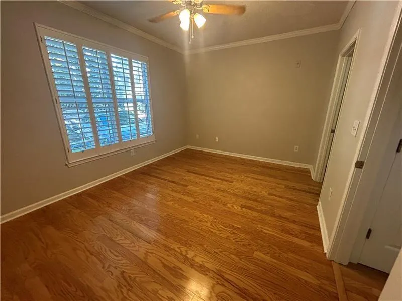 Empty room featuring hardwood / wood-style flooring, ceiling fan, and crown molding