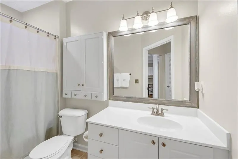 Bathroom featuring toilet, vanity, a shower with shower curtain, and tile patterned floors