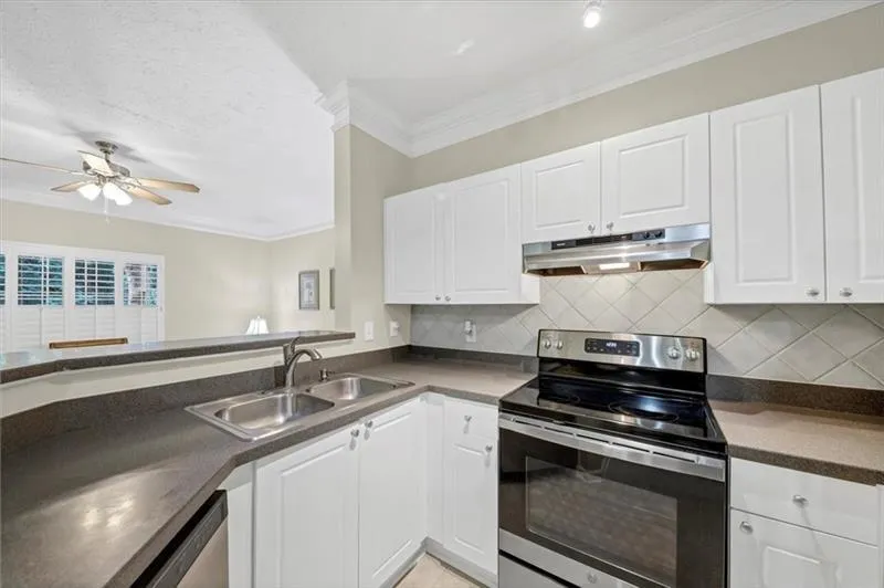 Kitchen featuring white cabinetry, sink, crown molding, and electric stove