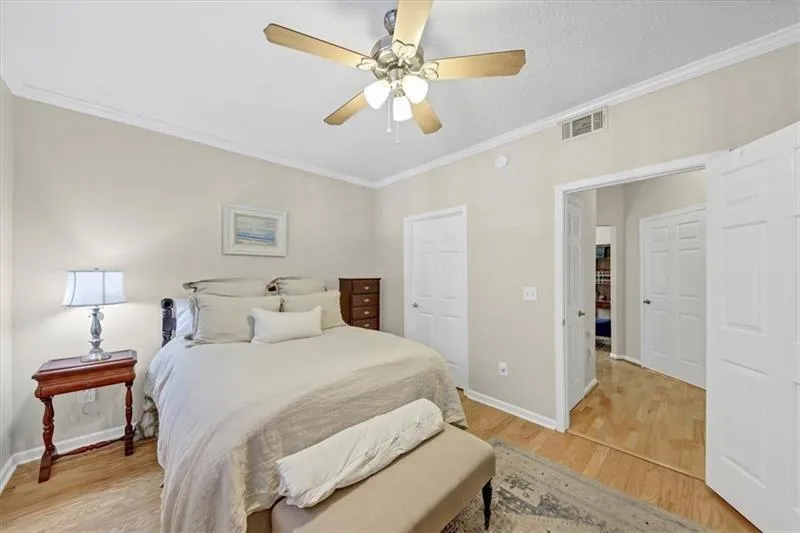 Bedroom featuring light hardwood / wood-style floors, ceiling fan, and crown molding