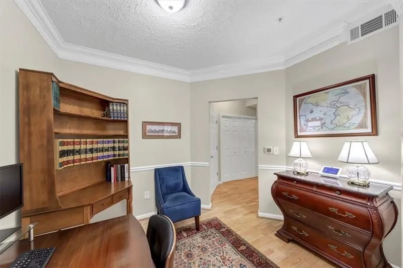 Living area with ornamental molding, light wood-type flooring, and a textured ceiling