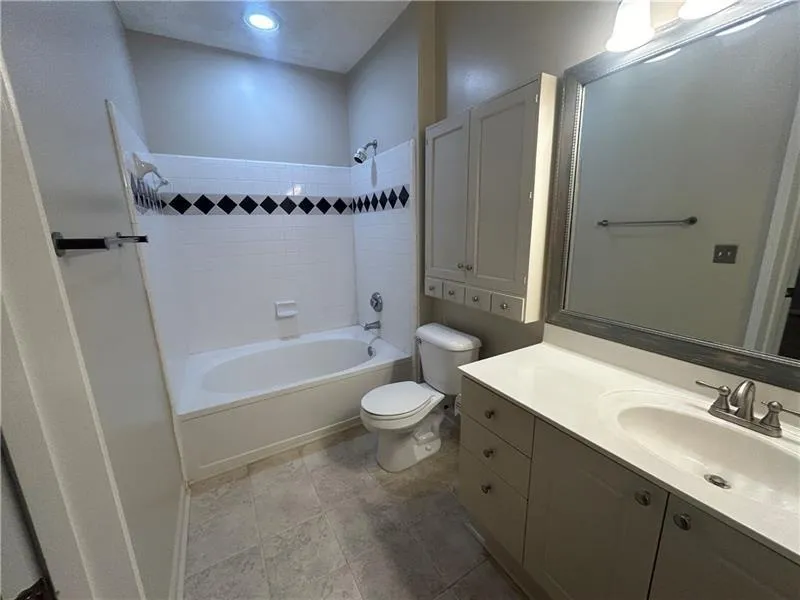 Full bathroom featuring vanity, tile patterned floors, toilet, and tiled shower / bath