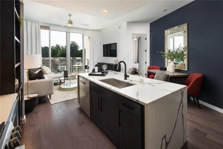 Kitchen with stainless steel dishwasher, dark hardwood / wood-style floors, sink, and a kitchen island with sink
