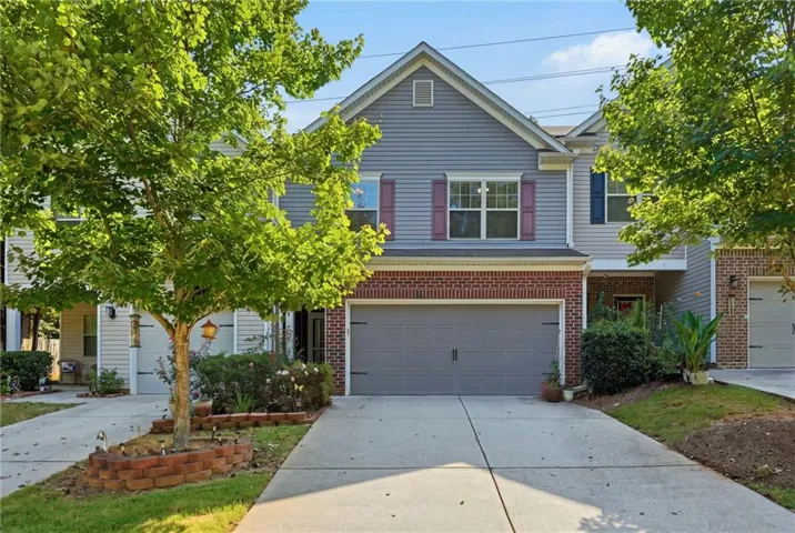 Siding and brick exterior with attached two-car garage, concrete driveway, and established landscaping