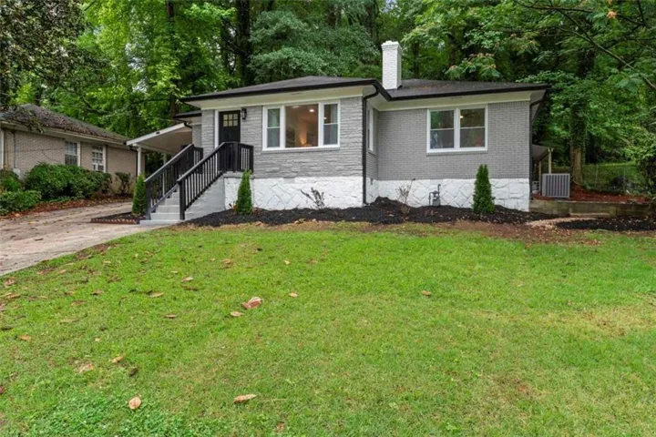 Exterior featuring a gray brick facade with white trim, a dark entry door, and a covered porch