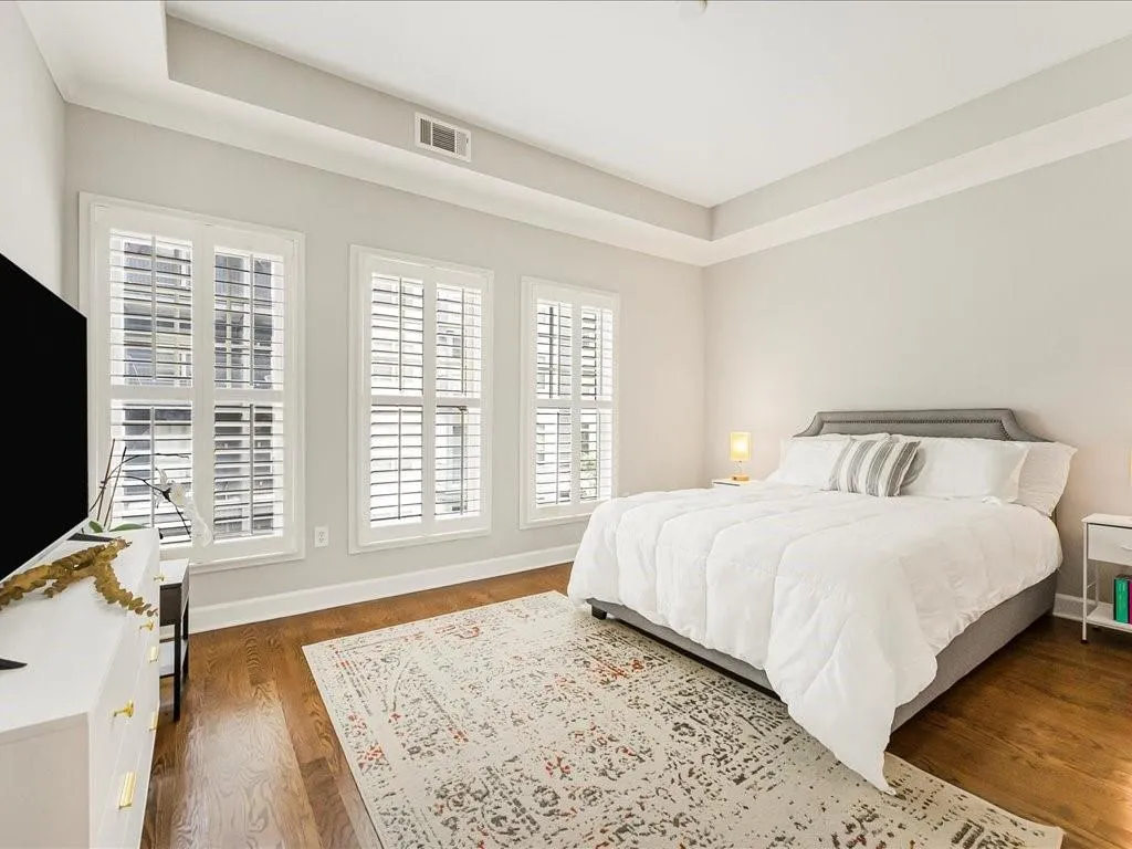 Bedroom featuring dark wood-style flooring and a tray ceiling