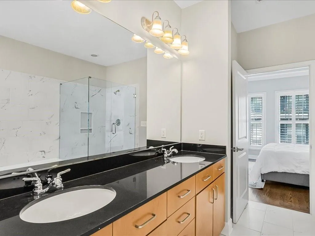 Bathroom with a marble finish shower, double vanity, and ensuite bathroom