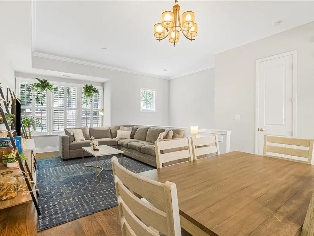 Living room with wood finished floors, a chandelier, and crown molding
