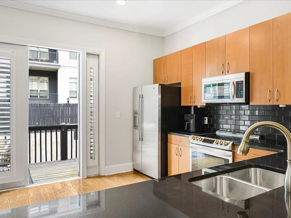 Kitchen with decorative backsplash, appliances with stainless steel finishes, ornamental molding, and light wood-type flooring