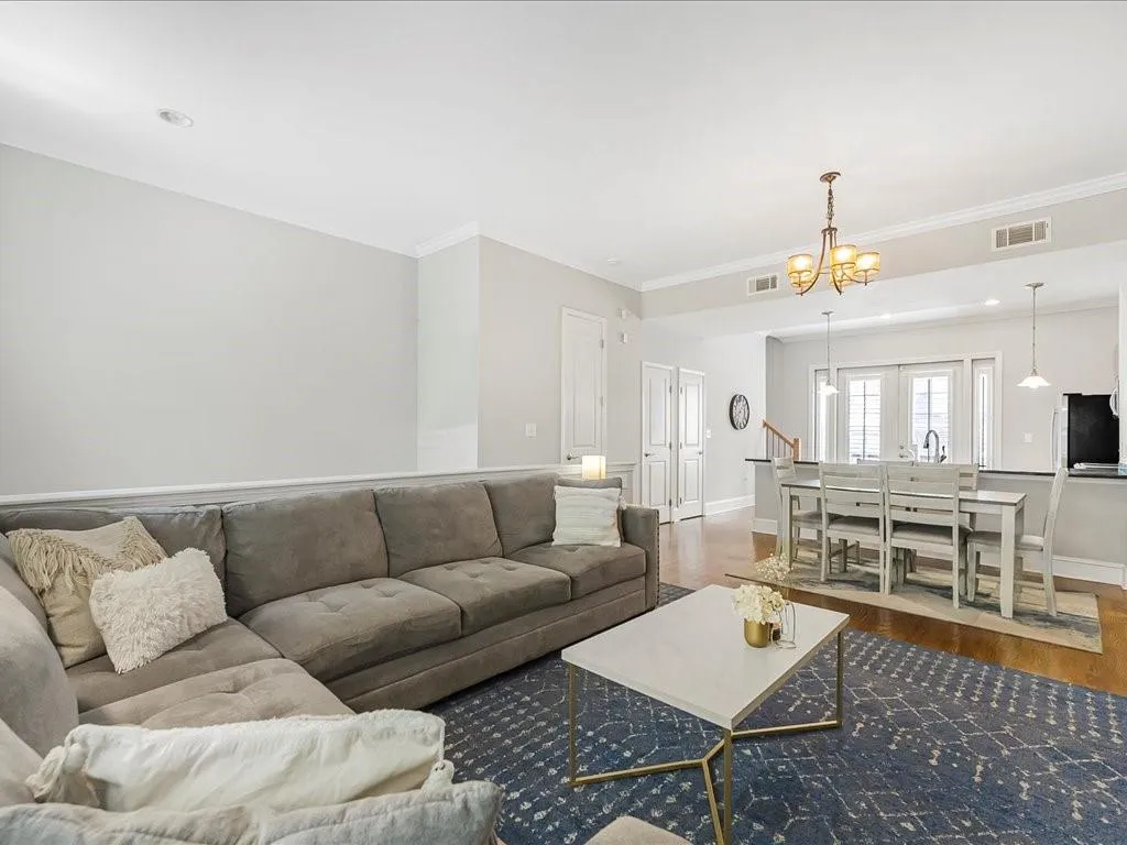 Living room featuring wood finished floors, ornamental molding, and a chandelier