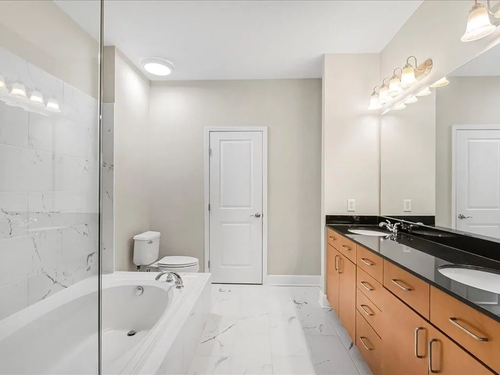 Full bathroom featuring marble look tile flooring, a bath, and double vanity