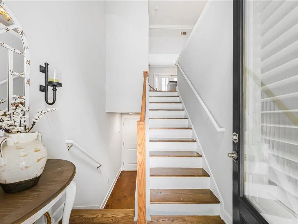 Stairs featuring wood finished floors and crown molding