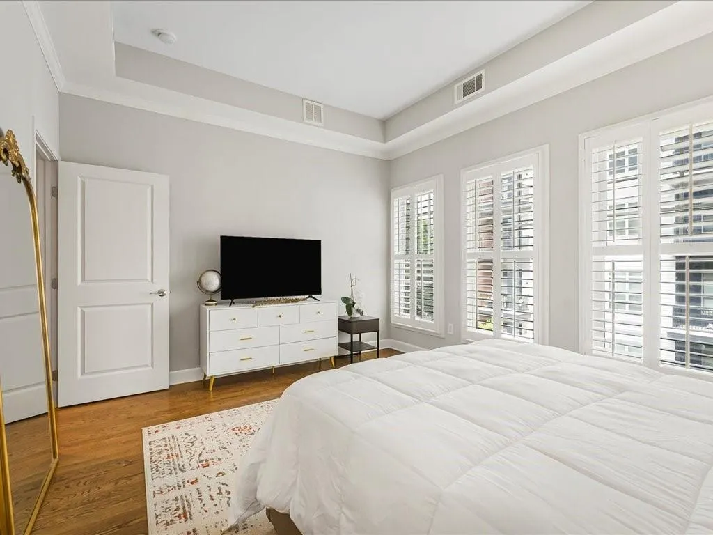 Bedroom featuring wood finished floors, a raised ceiling, and ornamental molding