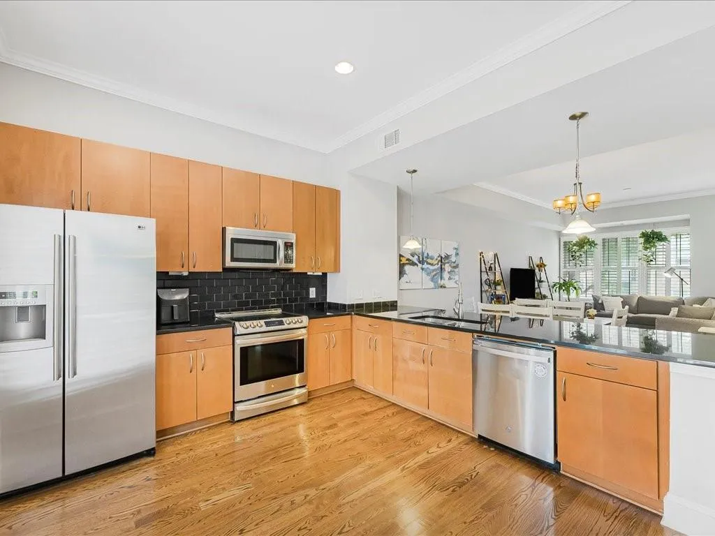 Kitchen featuring ornamental molding, stainless steel appliances, backsplash, open floor plan, and light wood finished floors