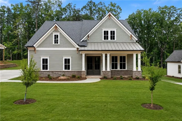 Craftsman-style home featuring light green siding, a dark gray shingle roof, and a covered front porch with white columns