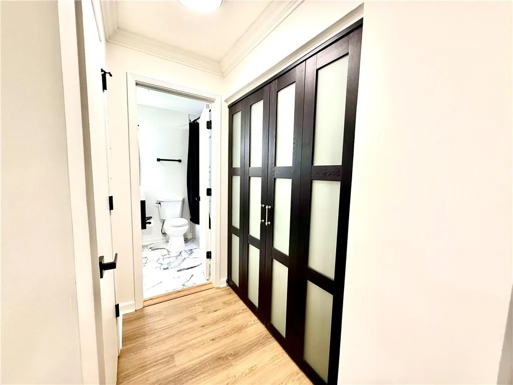 Corridor featuring light wood-style flooring and crown molding