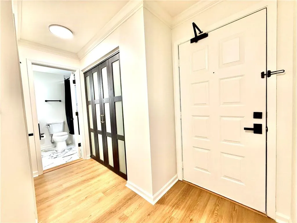Entryway with ornamental molding and light wood-style flooring