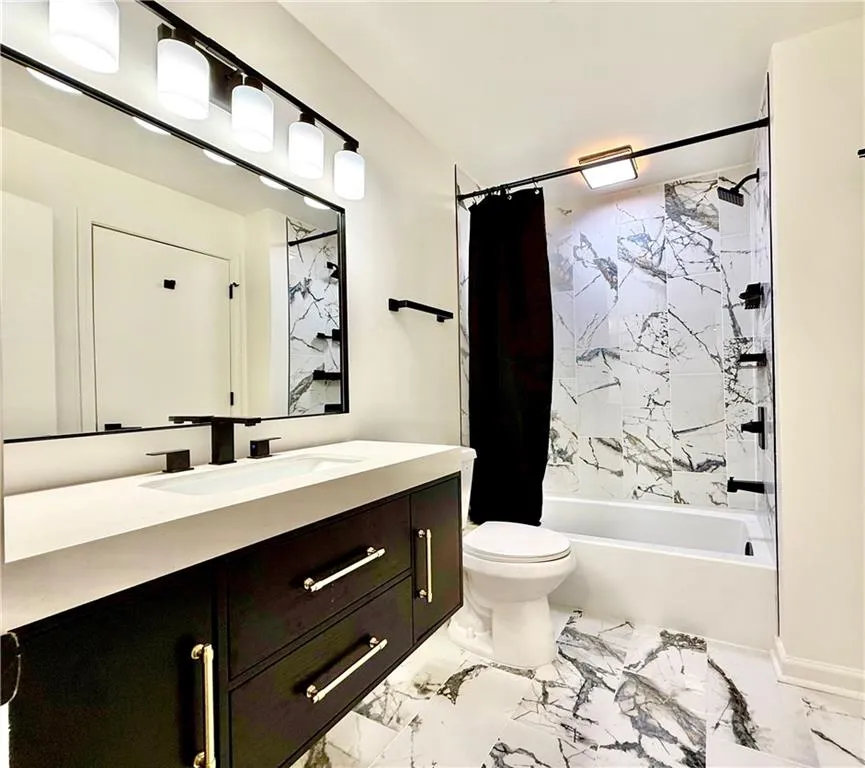 Bathroom with shower / tub combo with curtain, vanity, and light marble finish floors