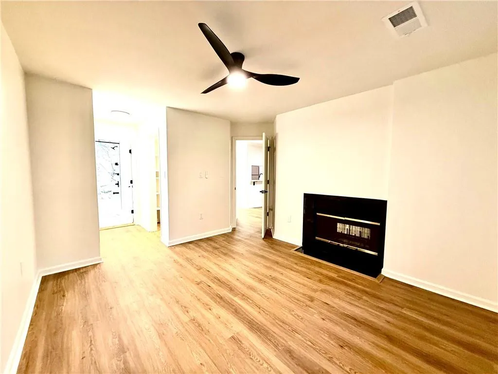 Unfurnished living room with light wood-style floors, ceiling fan, and a multi sided fireplace