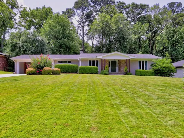 Ranch-style residence featuring a prominent front lawn, covered entry with stone accents, and a portico with support columns