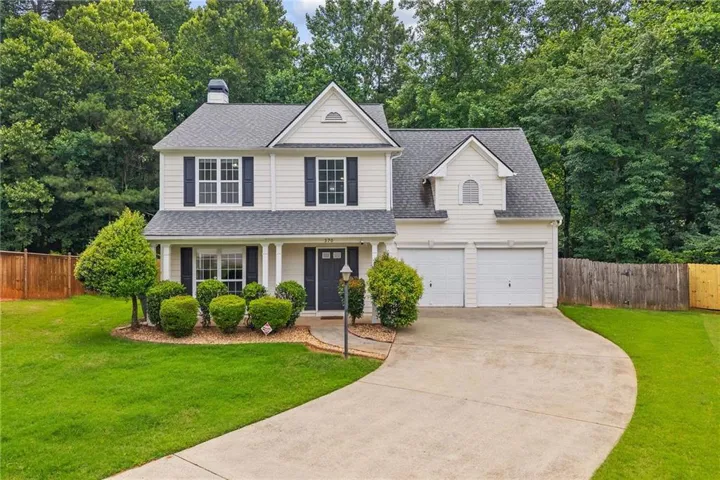 Two-story residence featuring white siding, black window shutters, a covered front entry with columns, a two-car garage, and a concrete driveway