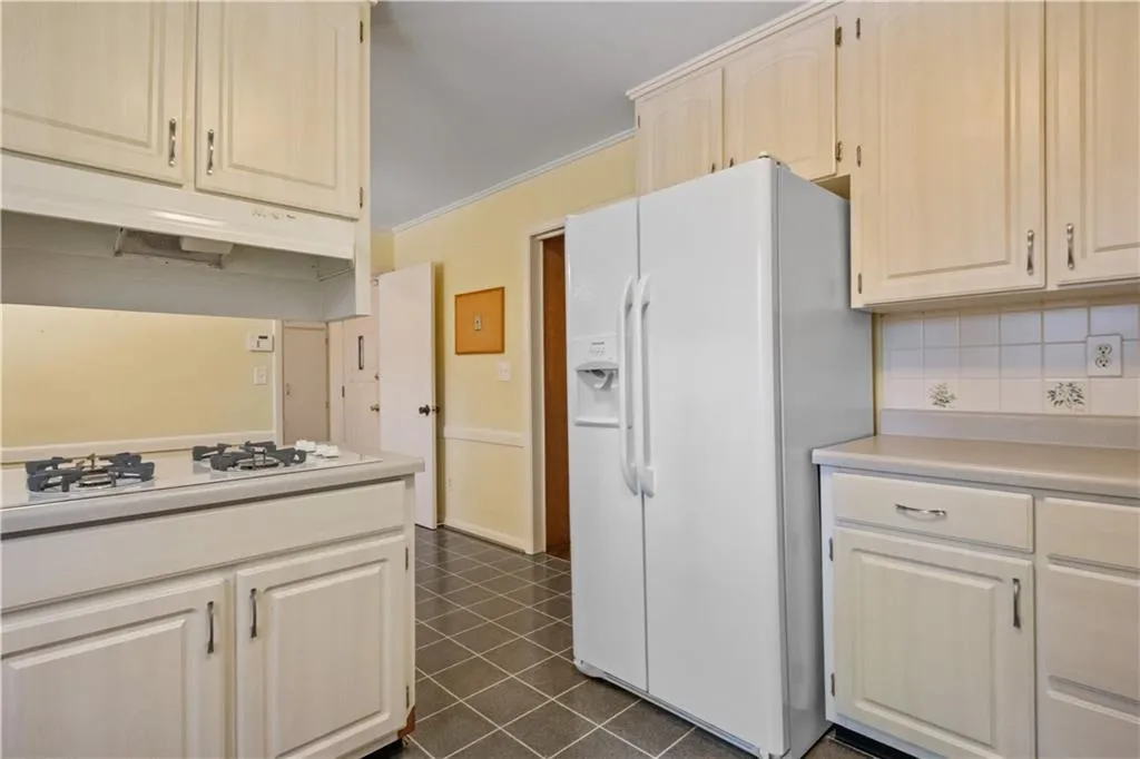 Kitchen featuring crown molding, white appliances, and decorative backsplash Kitchen featuring crown molding, white appliances, and decorative backsplash