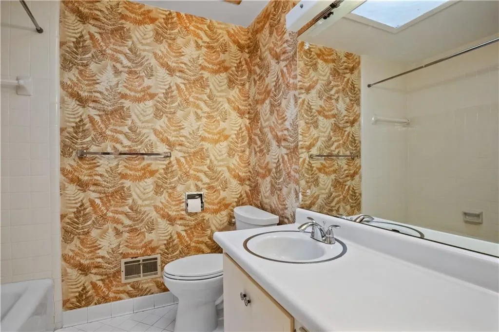 Full bathroom featuring vanity, tiled shower / bath, tile patterned flooring, a skylight, and toilet Full bathroom featuring vanity, tiled shower / bath, tile patterned flooring, a skylight, and toilet