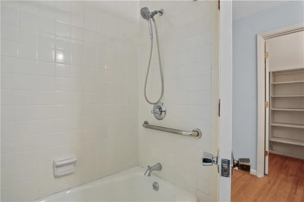 Bathroom featuring tiled shower / bath combo and hardwood / wood-style flooring Bathroom featuring tiled shower / bath combo and hardwood / wood-style flooring