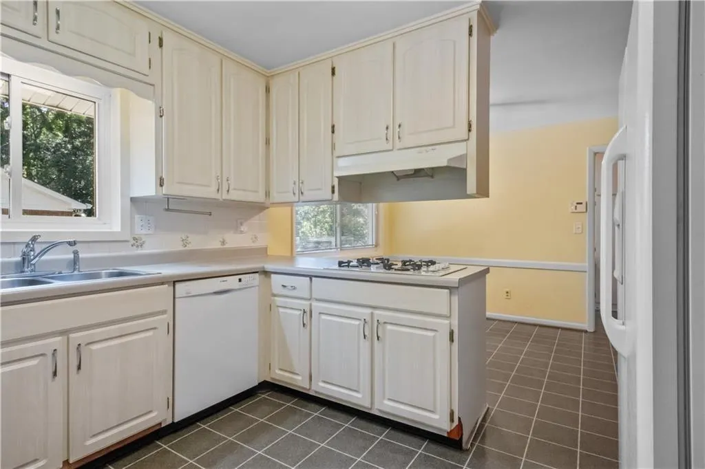 Kitchen featuring kitchen peninsula, a healthy amount of sunlight, white appliances, and sink Kitchen featuring kitchen peninsula, a healthy amount of sunlight, white appliances, and sink