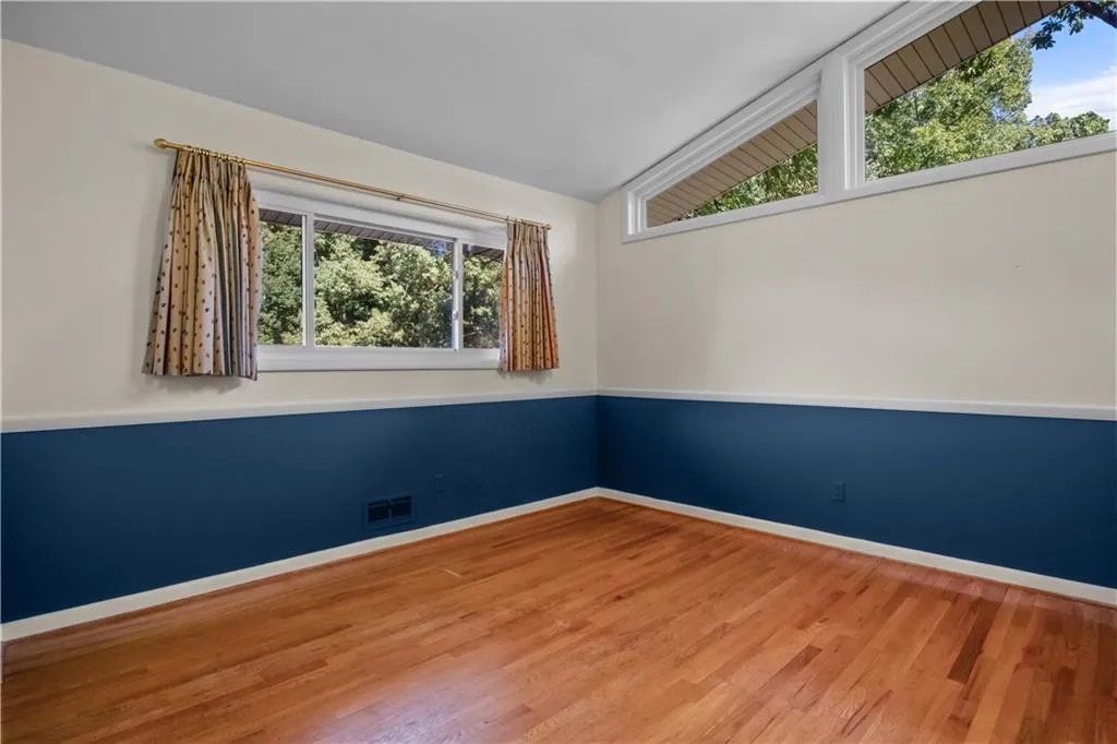 Empty room with hardwood / wood-style flooring, vaulted ceiling, and a wealth of natural light Empty room with hardwood / wood-style flooring, vaulted ceiling, and a wealth of natural light