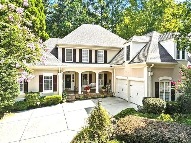 View of front of property featuring covered porch, stucco siding, driveway, a shingled roof, and a garage